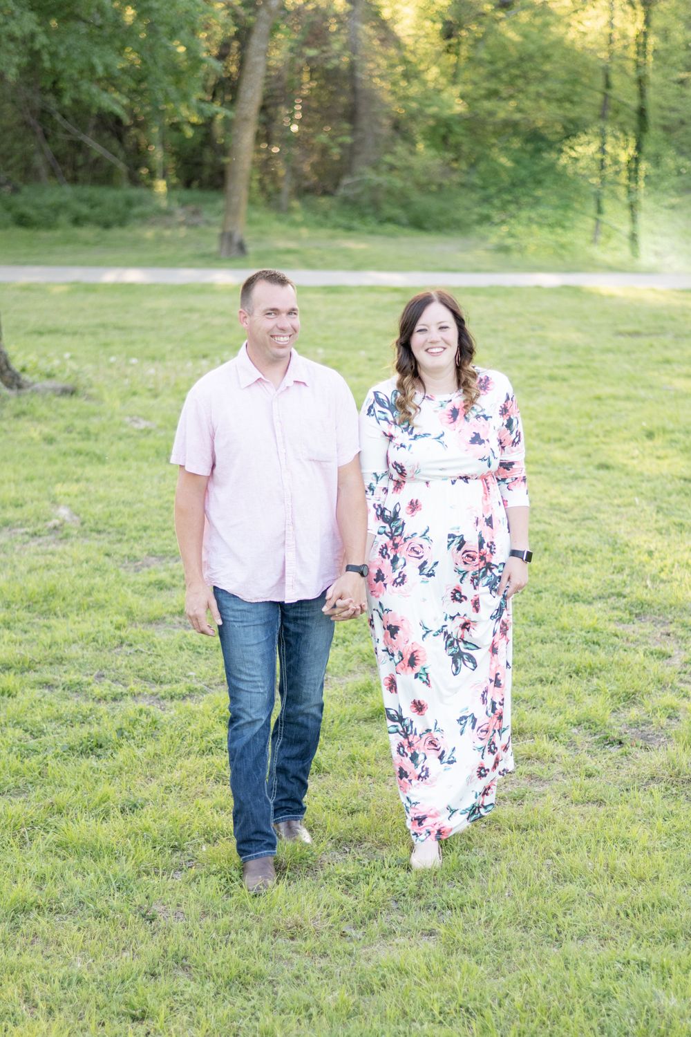 Couple walking together on grassy lawn wearing coordinated pink and floral outfits.