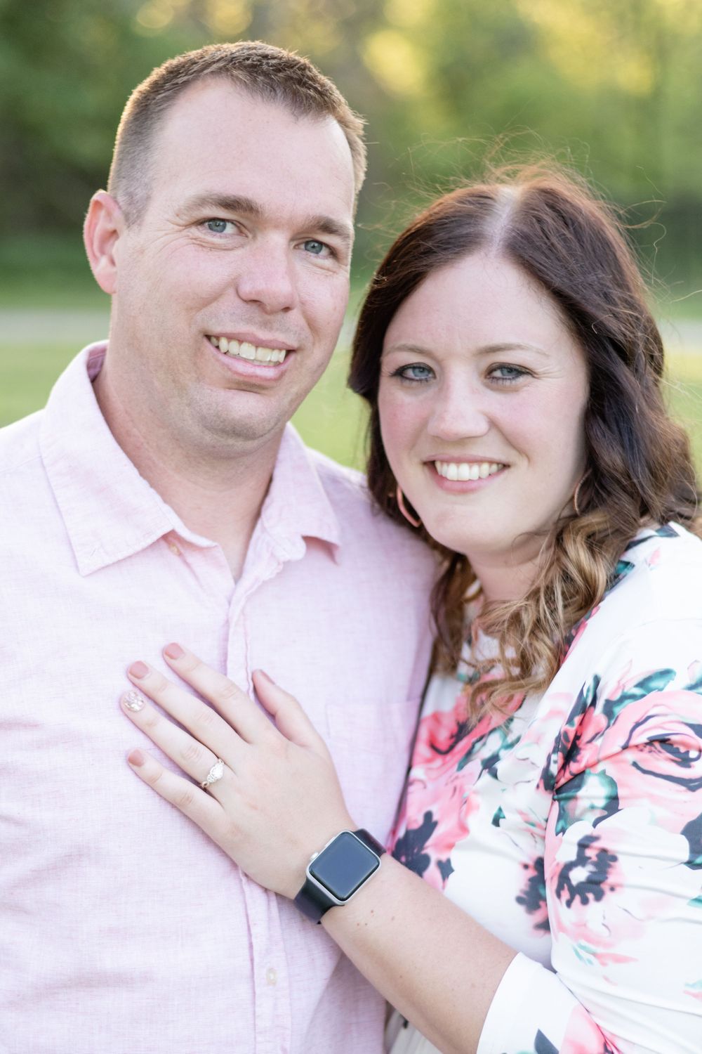 Happy couple in coordinated pink outfits smiling during outdoor portrait session.