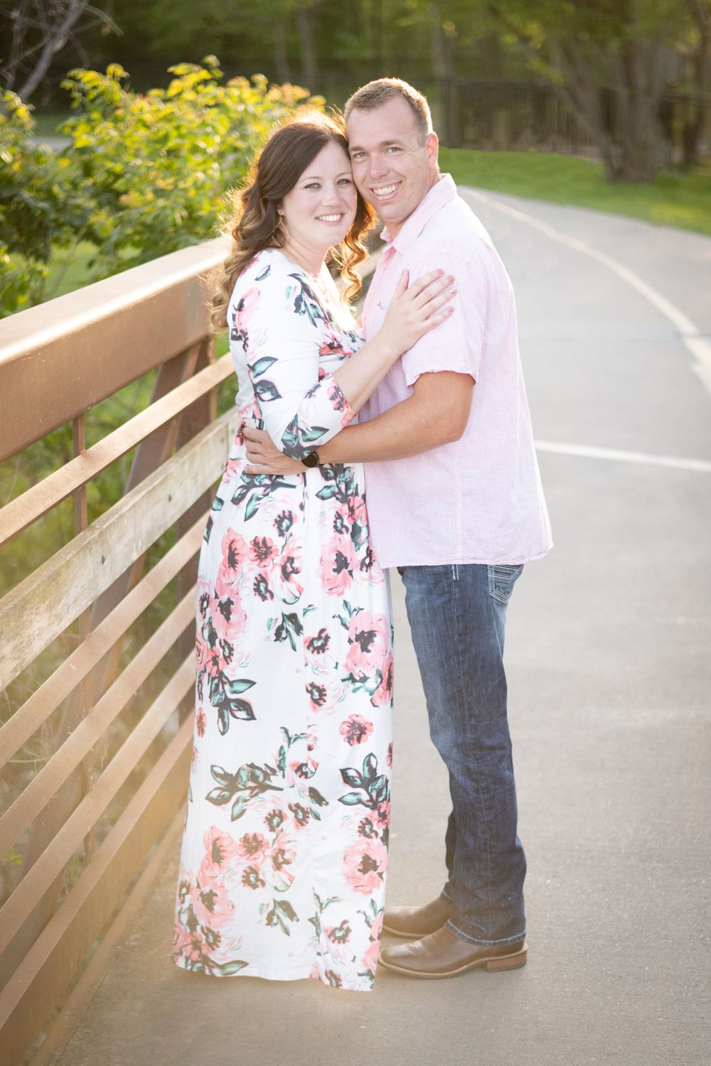 Romantic portrait of couple in coordinated outfits standing on wooden bridge pathway.