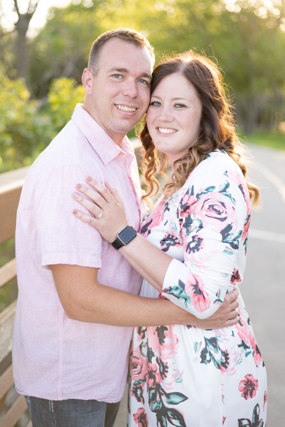 Joyful couple embracing during sunset photoshoot wearing pink and floral attire.