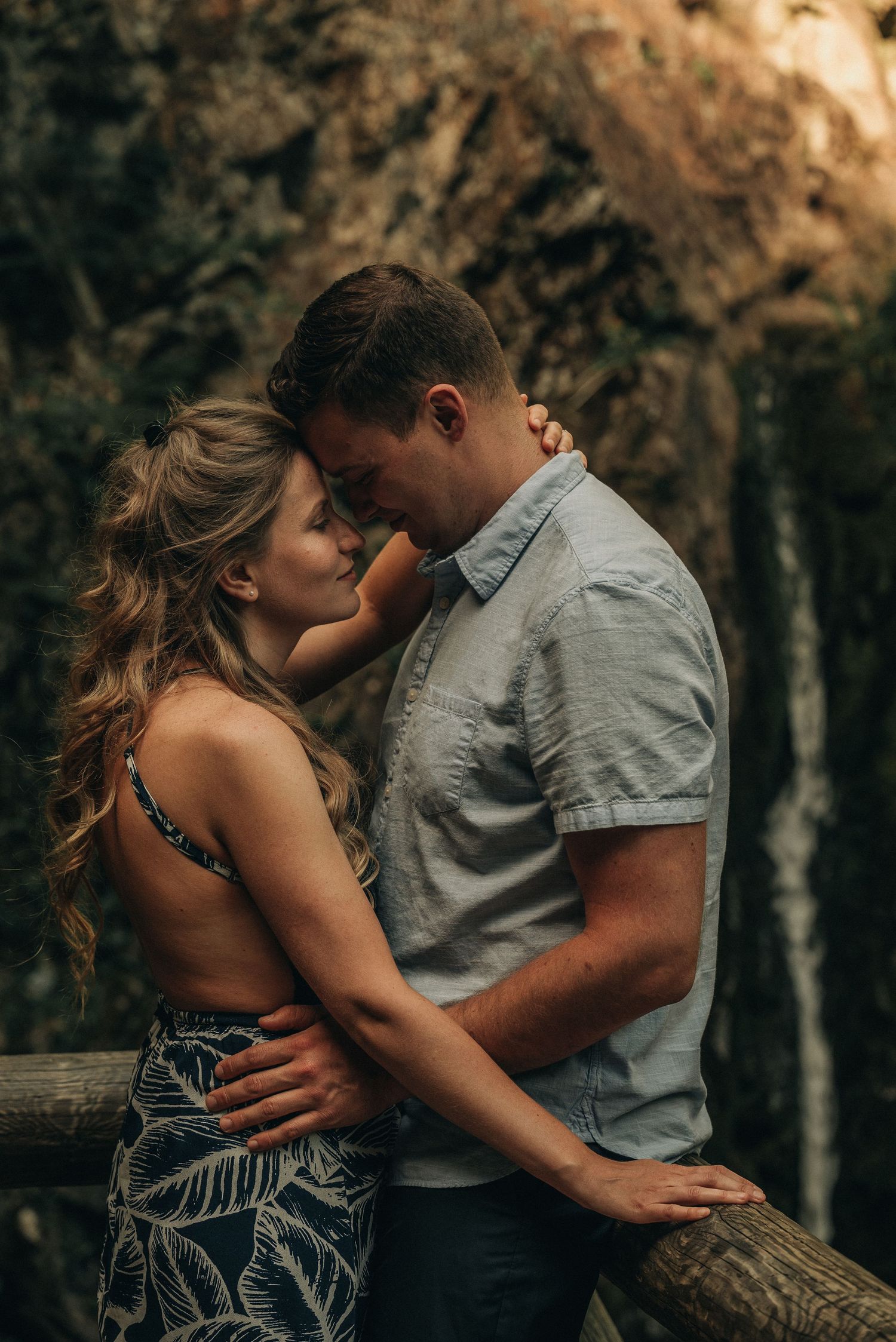 A romantic outdoor embrace between a couple in casual attire against a natural backdrop.