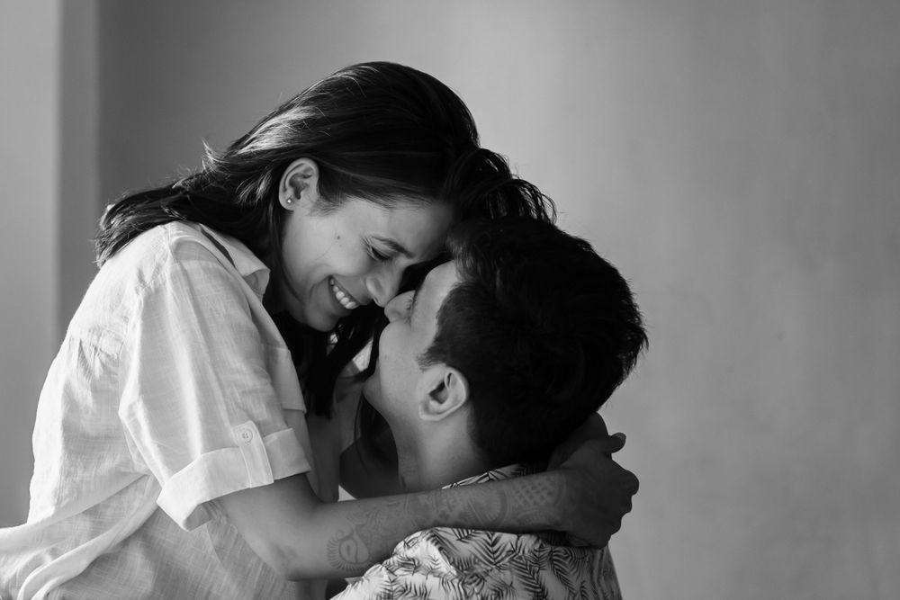 A tender black and white intimate portrait of two people sharing a close embrace and joyful moment together.