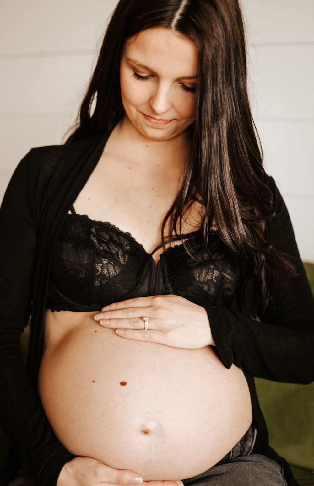 Maternity boudoir photo showing pregnant belly with black lace and cardigan.