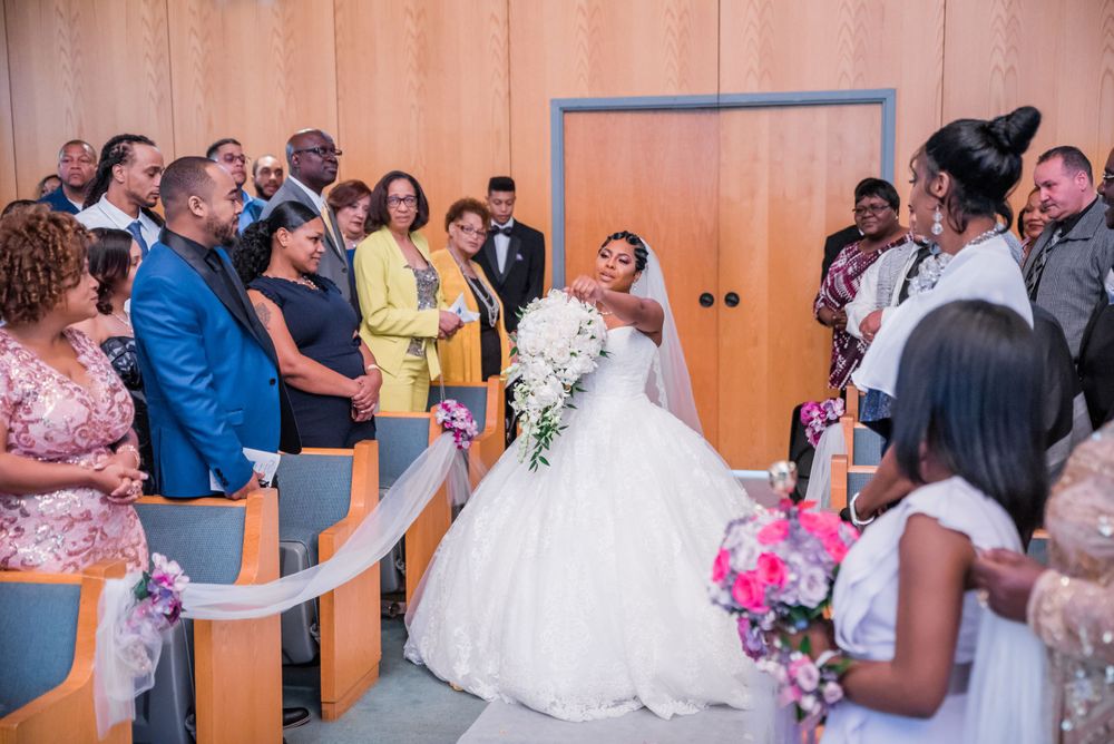 Wedding ceremony with guests seated in rows watching procession in modern chapel setting.