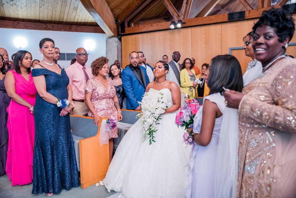 Wedding party and guests in colorful formal attire gather during chapel ceremony.