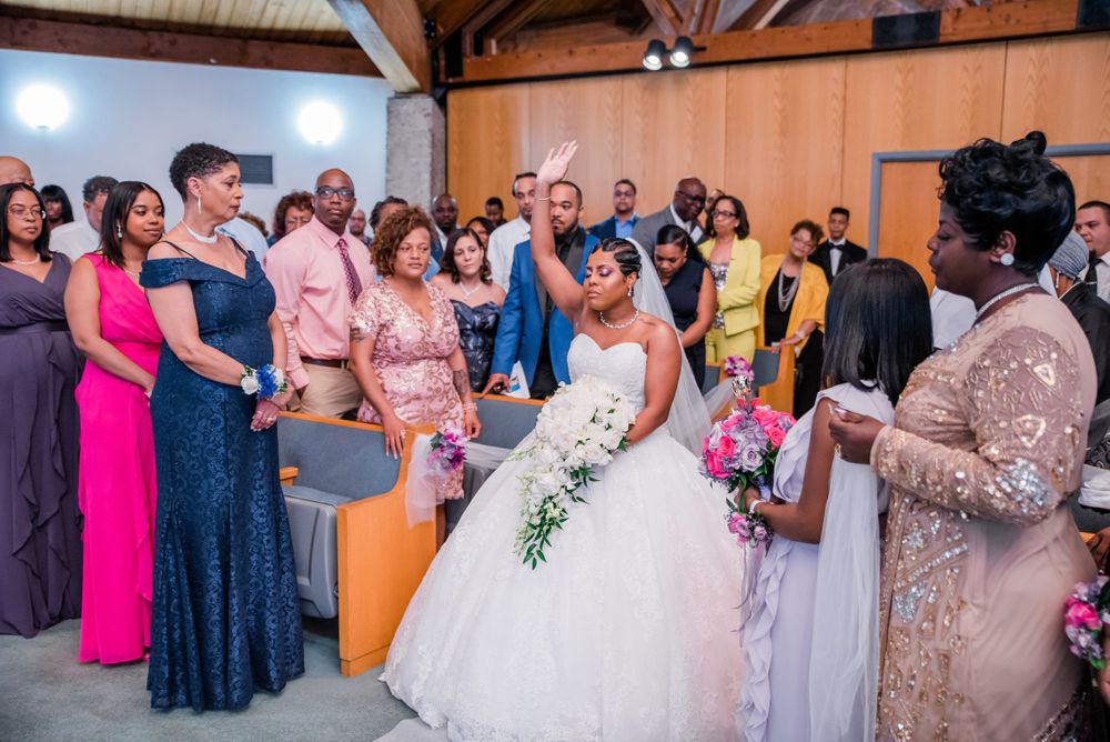 Wedding ceremony guests gather in a venue with wooden beams and orange walls during an emotional moment.