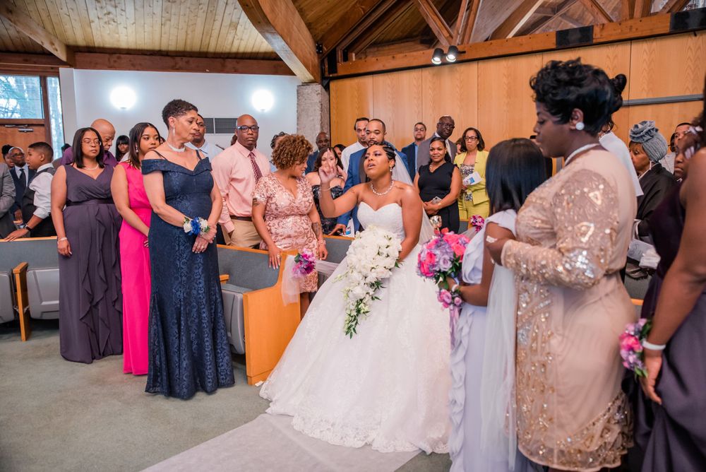 Wedding guests in formal attire stand together during ceremony in wooden-beamed venue.