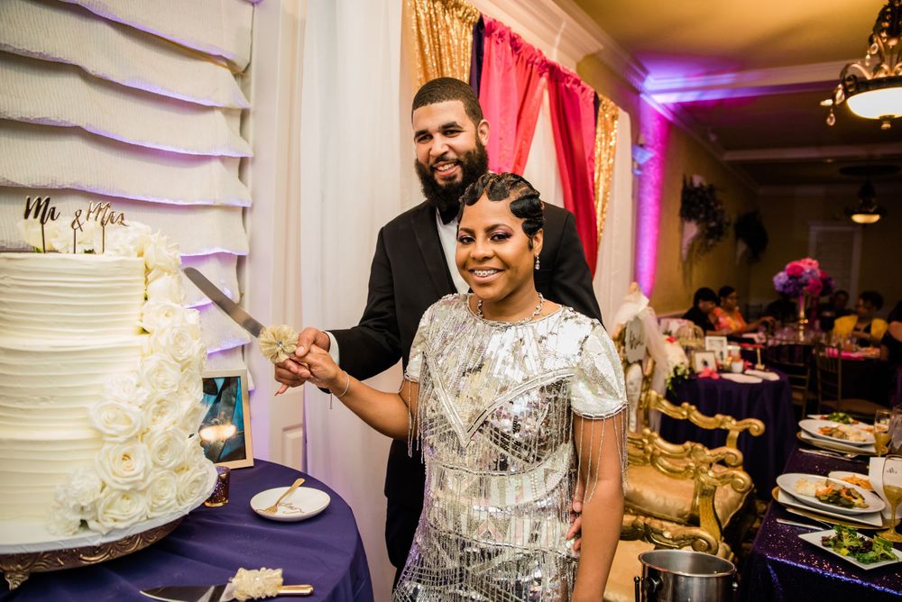 Wedding couple cuts their elegant white tiered cake at reception.