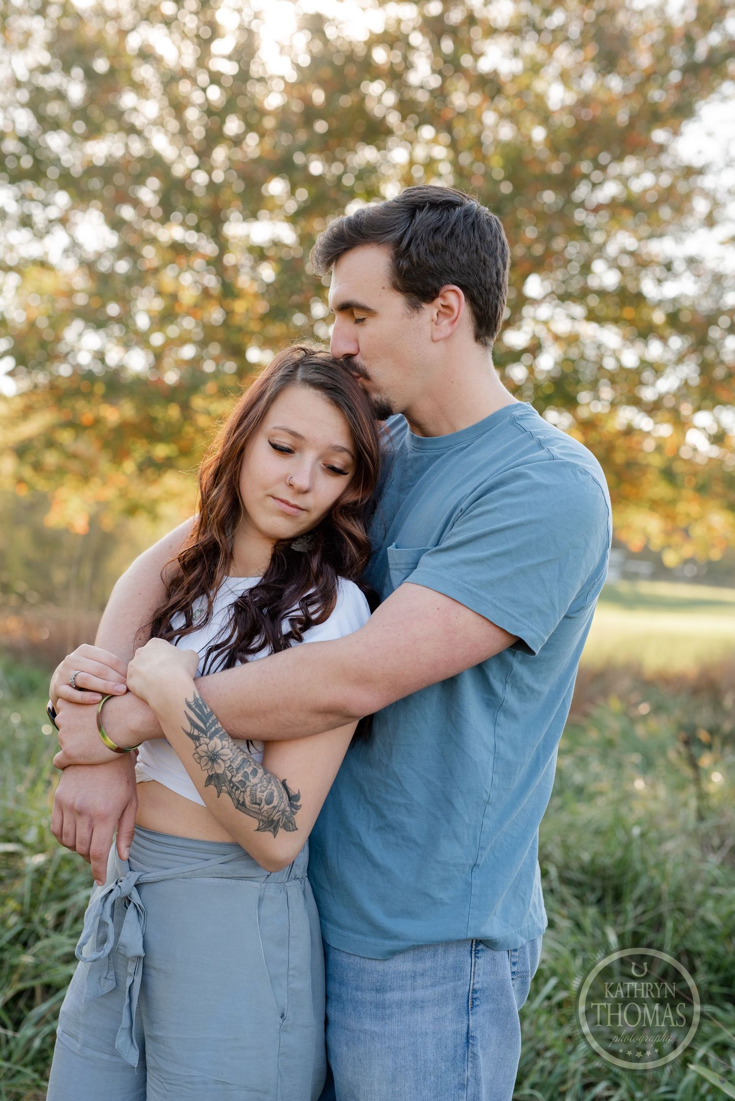 A couple sharing an intimate moment while standing in golden evening light outdoors.