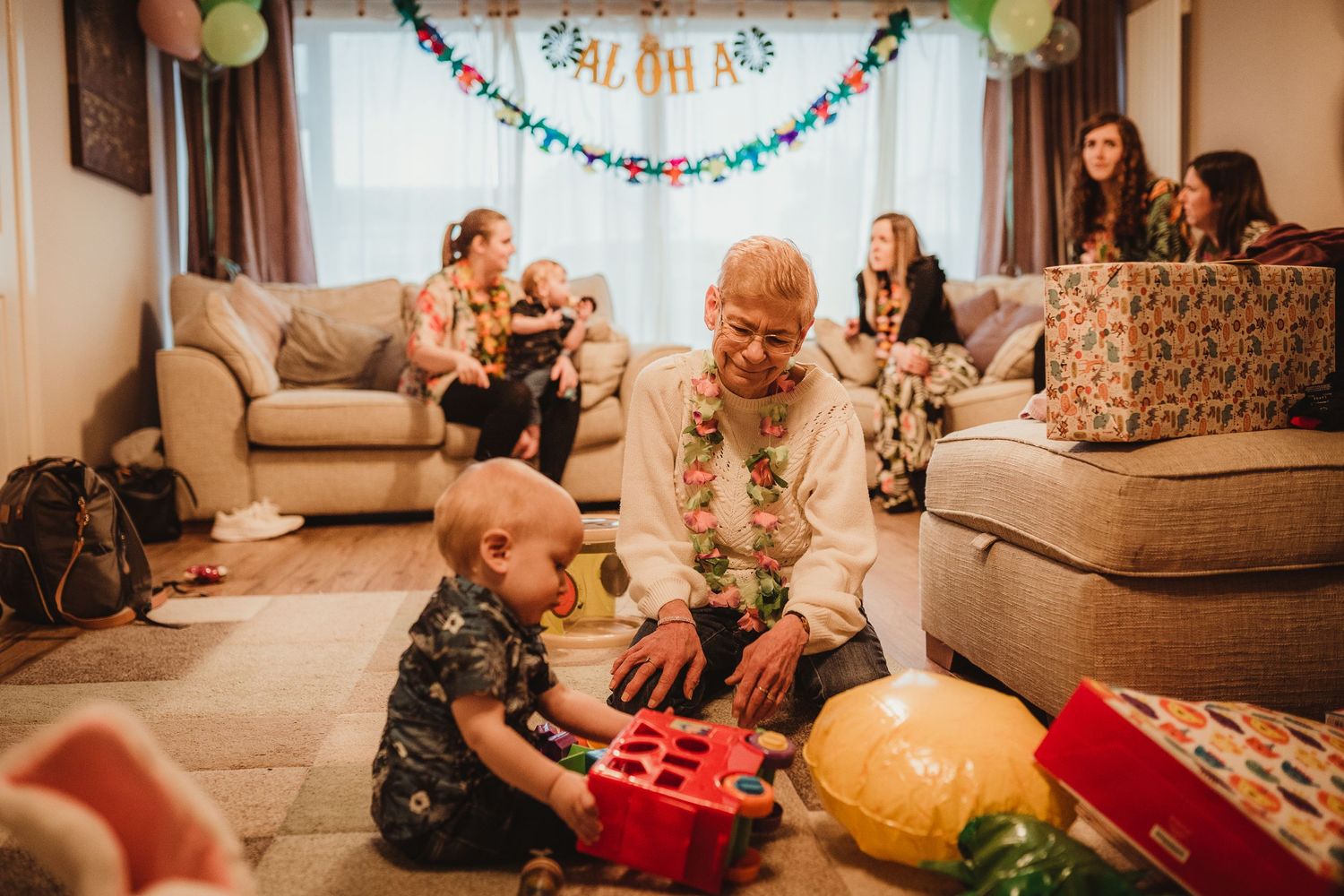 birthday boy sitting on the floor with his great-grandma playing with his toys