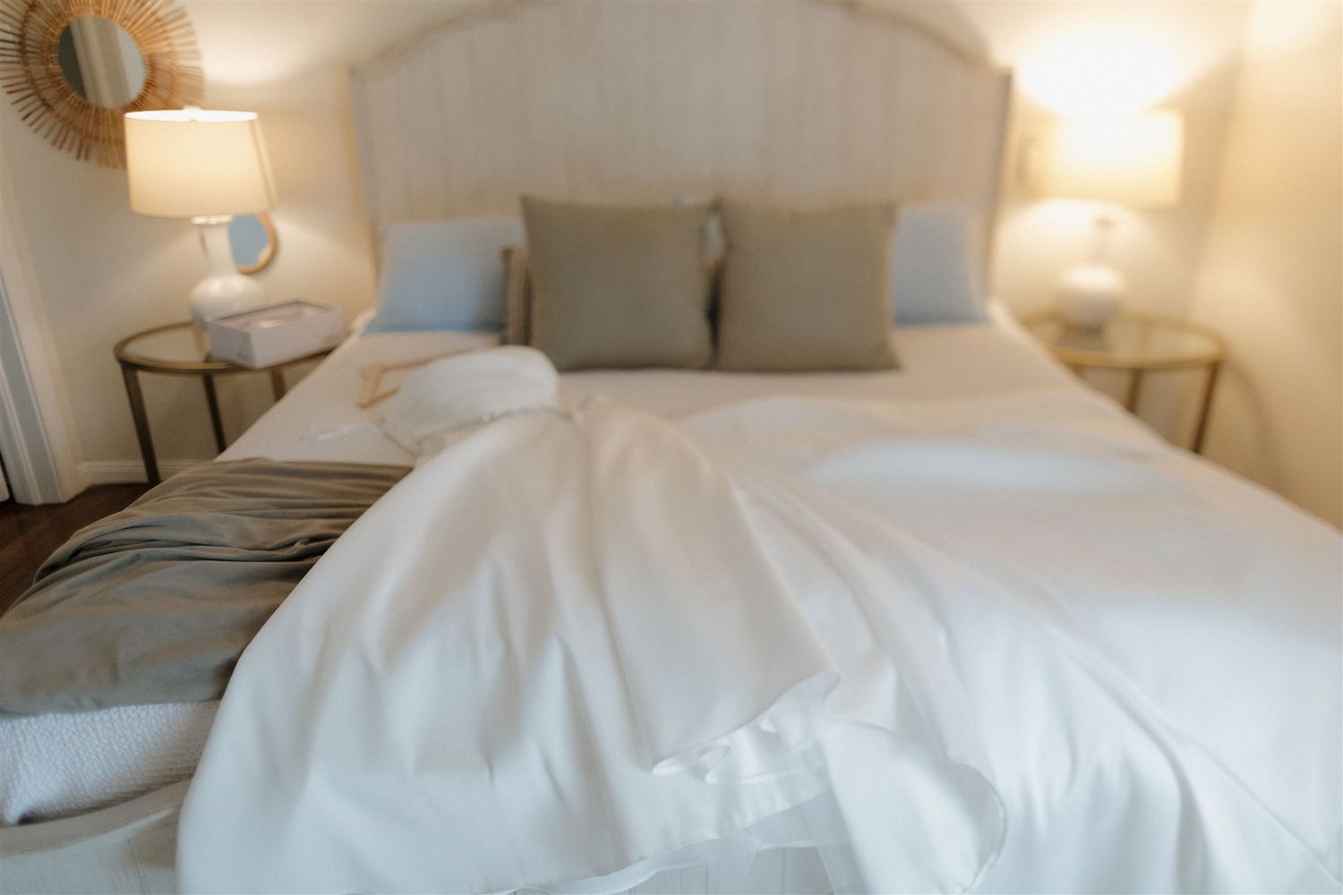 A cozy bedroom interior with white bedding and soft grey accent pillows.