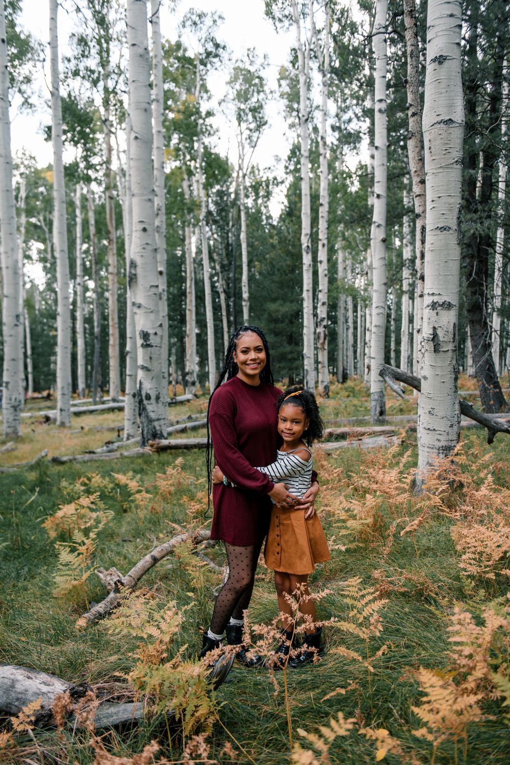 Mother and child posing among tall white aspen trees with golden ferns.