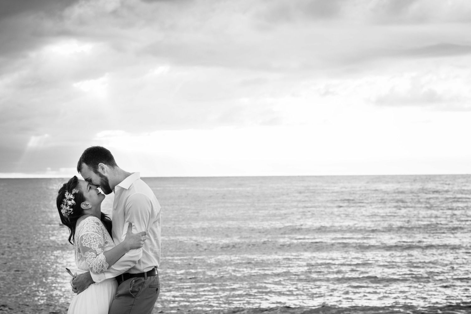 Couple embrace on Barcelona beach after their secret wedding elopement.