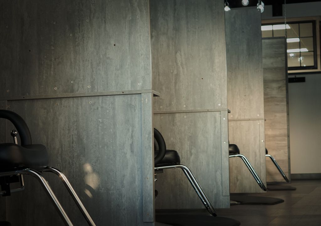 Modern interior with concrete walls and sleek chrome bar stools in dimly lit space.