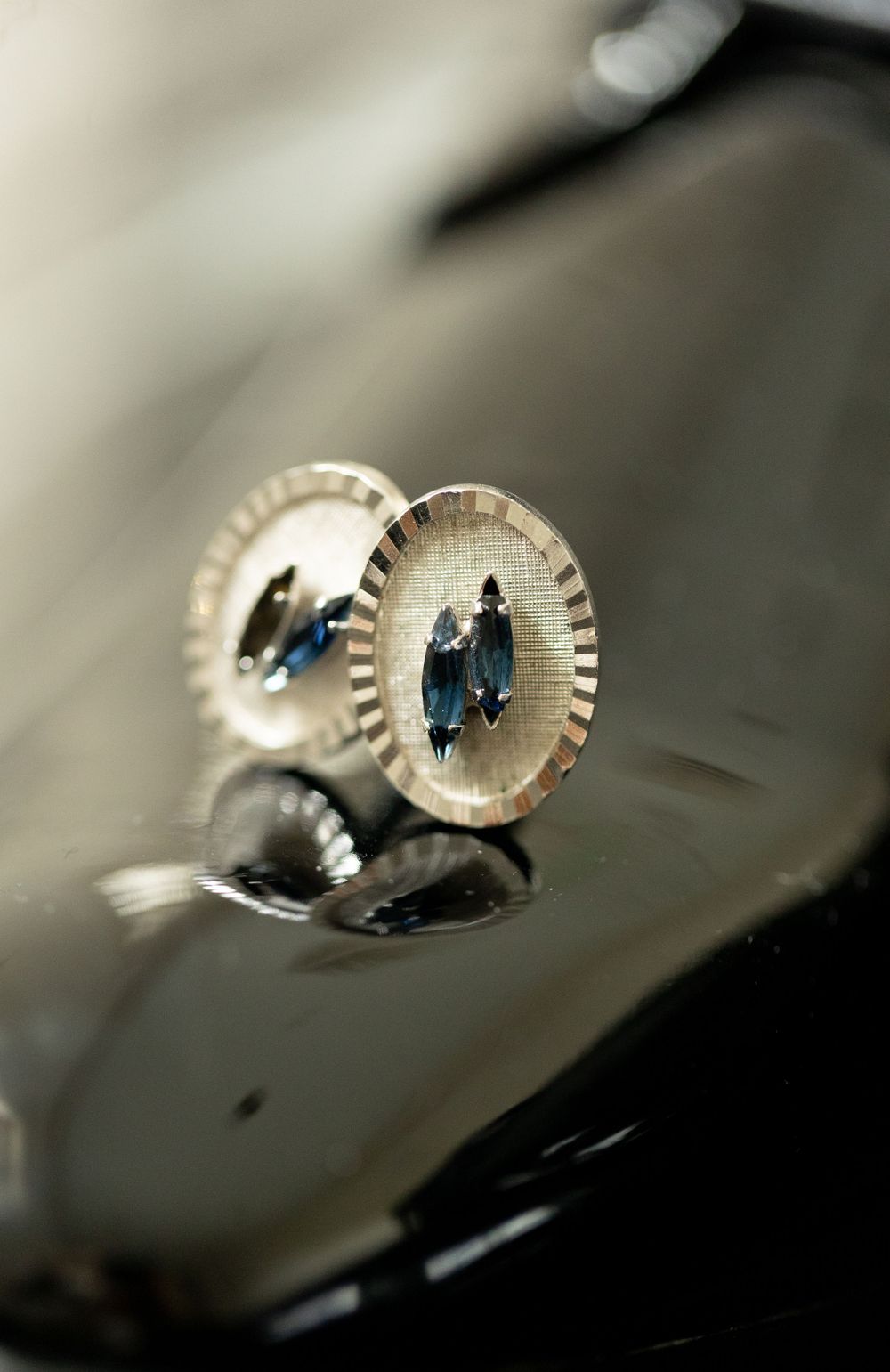 Artistic macro shot of wedding cufflinks reflecting a couple's silhouette.