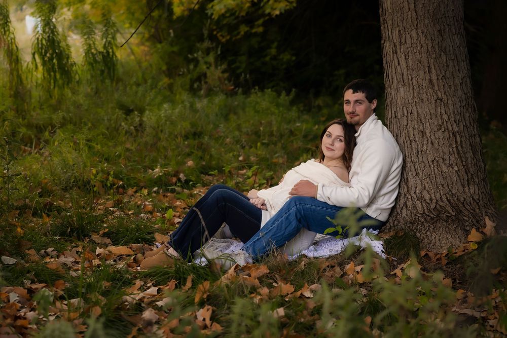 young couple sitting under a tree autumn photos