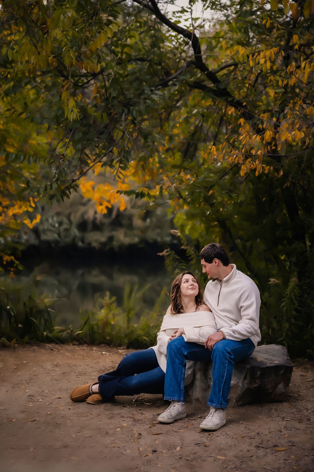 Young couple lautumn photos sitting on a river band