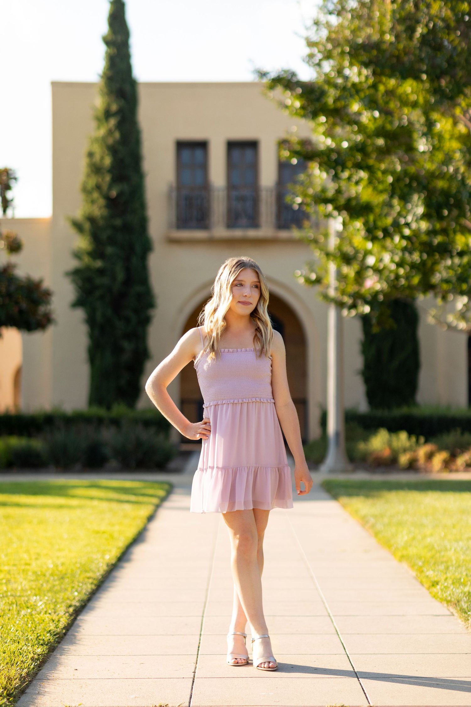 A high school senior wearing a flowing mauve chiffon evening gown with thigh slit and sweetheart neckline swirls elegantly