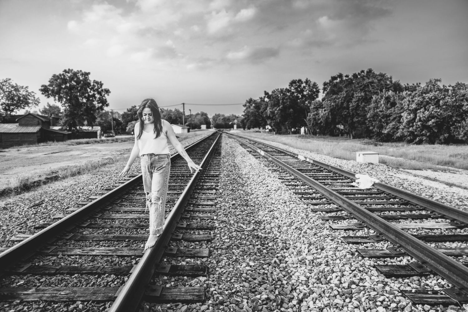 Black and white artistic photo of railroad tracks stretching into distance with trees.
