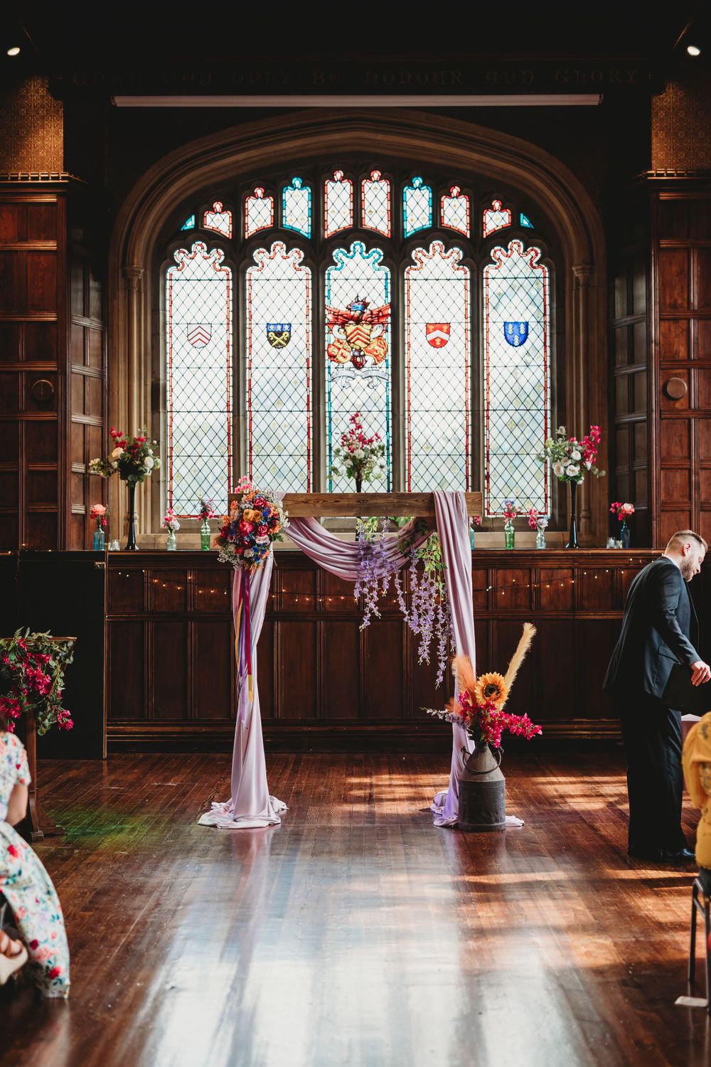 A grand hall with gothic windows and draped fabric decorations for a wedding ceremony.