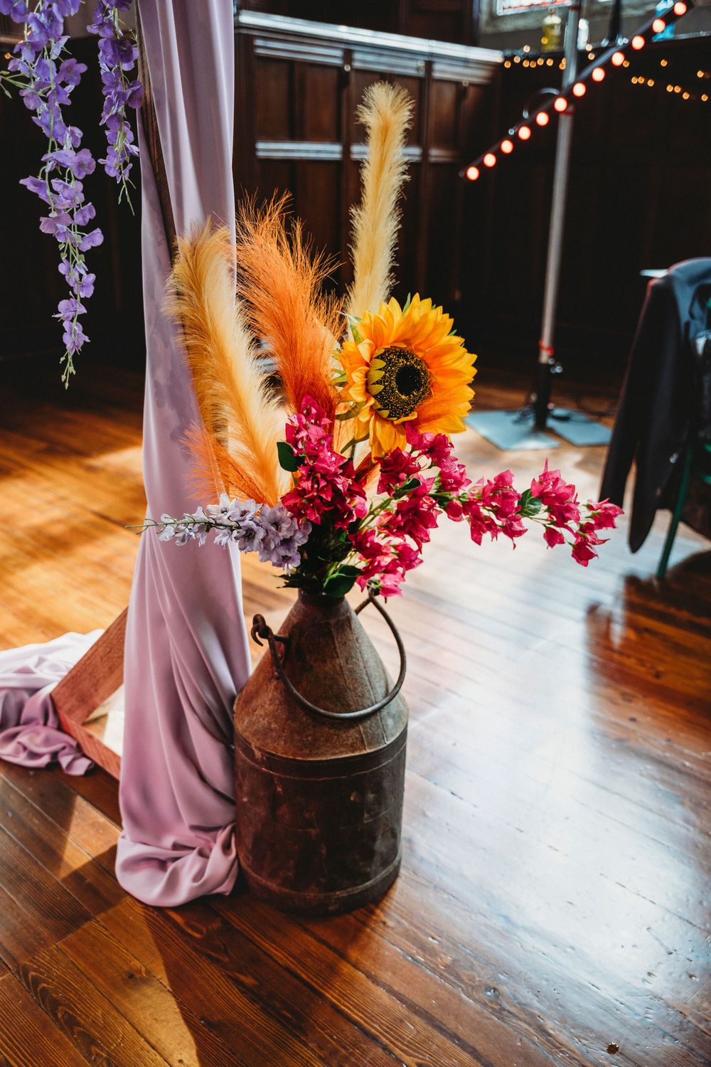 Rustic floral arrangement with sunflowers and dried flowers in vintage container.