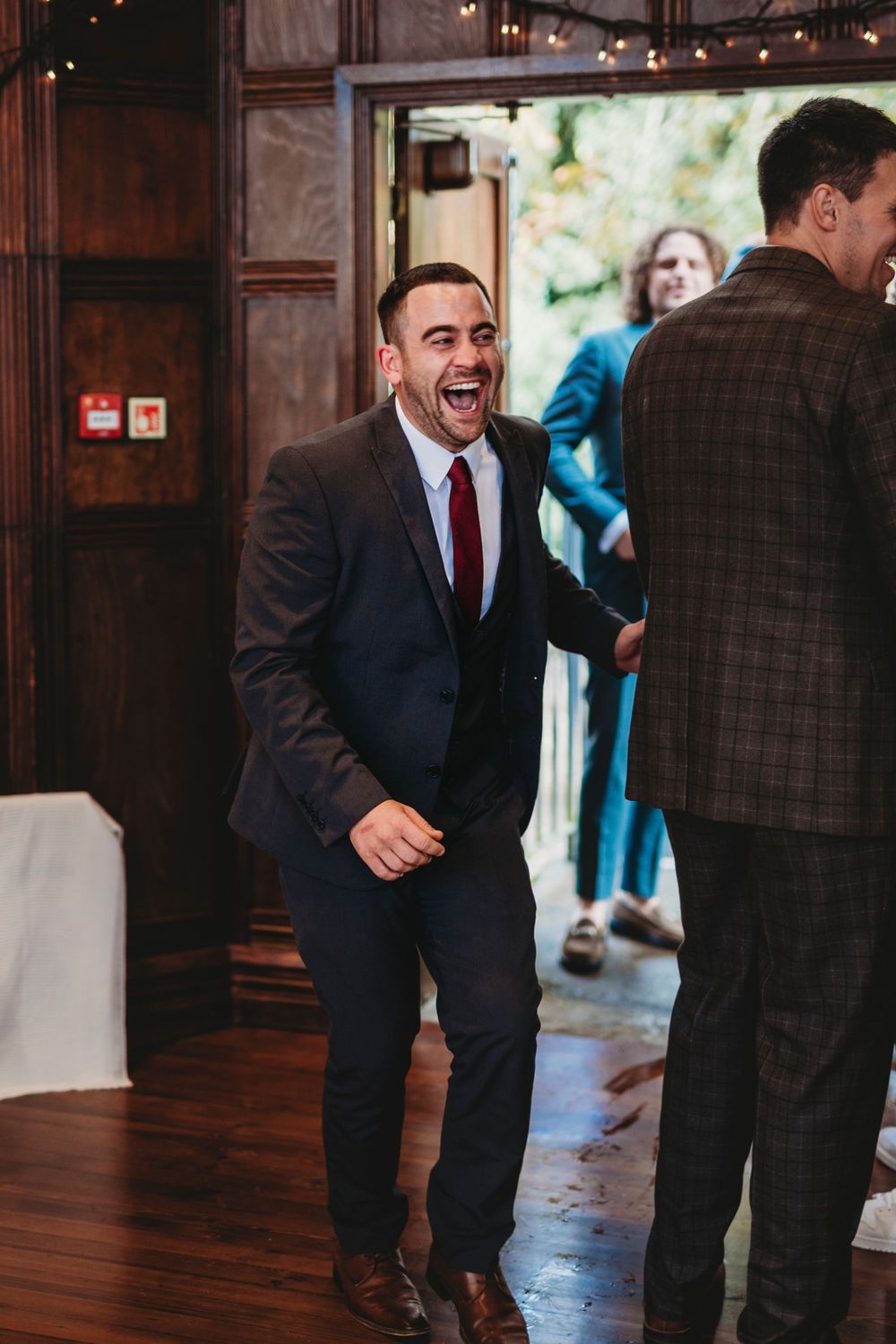 Guests celebrate on a polished wooden dance floor under ambient lighting at a wedding reception.