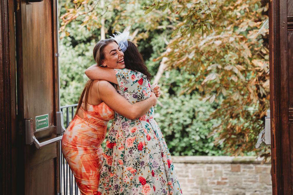 Guests in colorful summer dresses mingling outside a historic building.