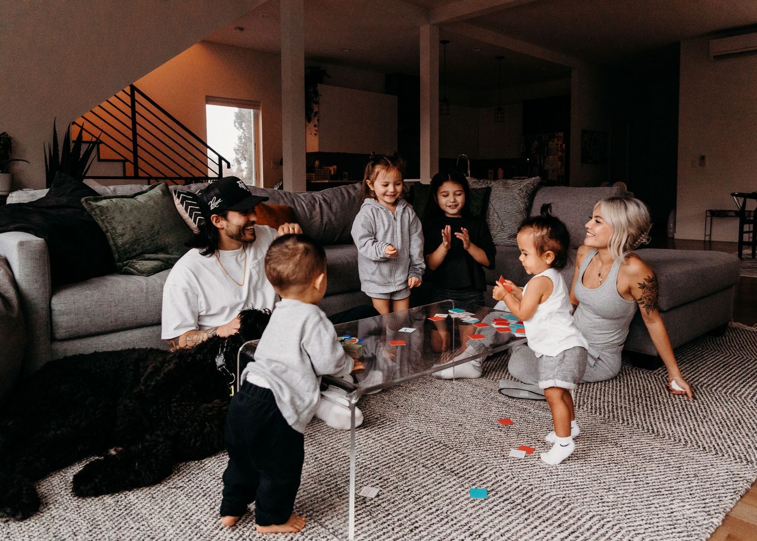 Group sitting in a circle on gray carpet for casual indoor gathering.
