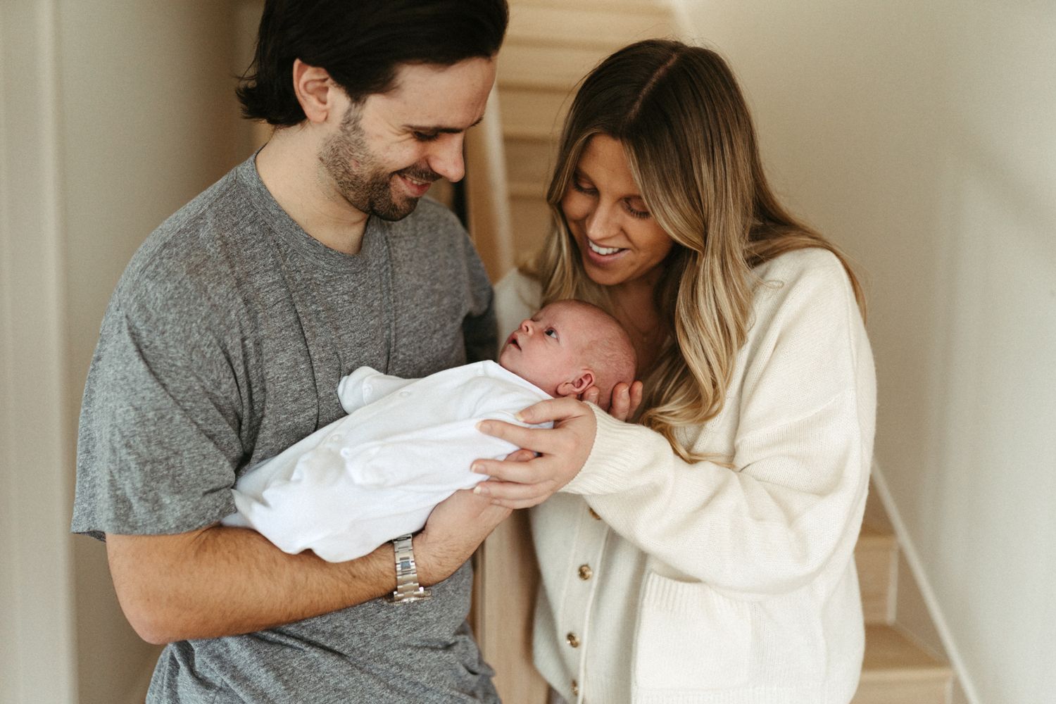 A cozy indoor scene of parents gazing lovingly at their newborn baby. In-home, Newborn photoshoot photographer, South Hams & Plymouth