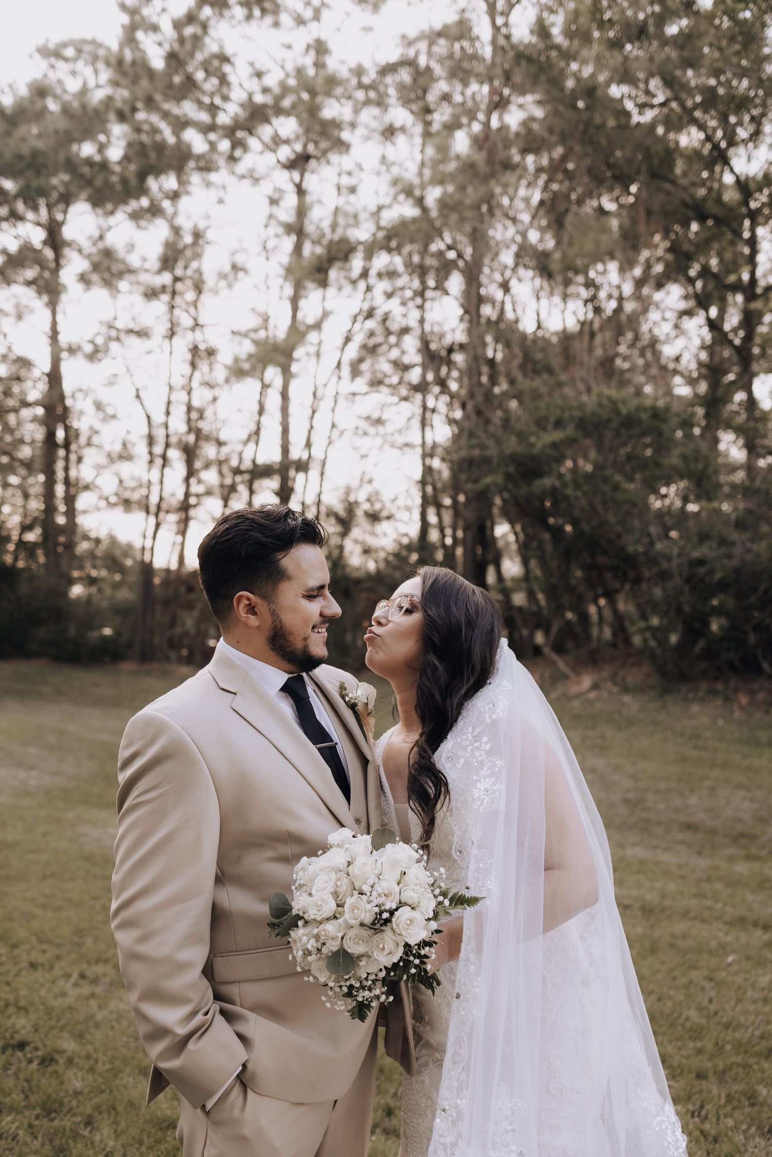 A romantic portrait of newlyweds sharing a moment in a wooded outdoor setting.