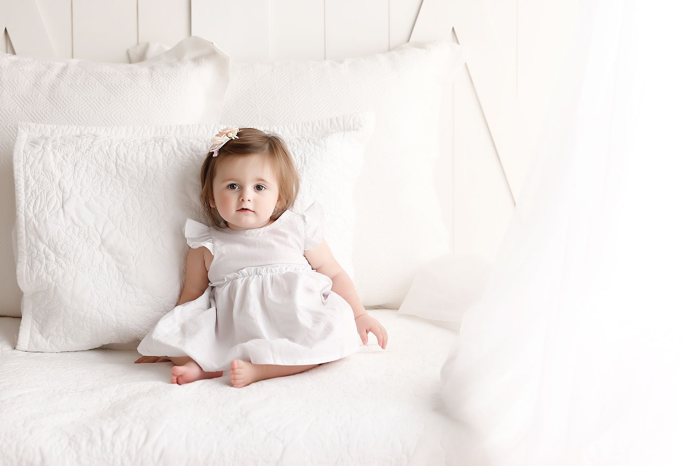 One year old posed on a white bed photograph