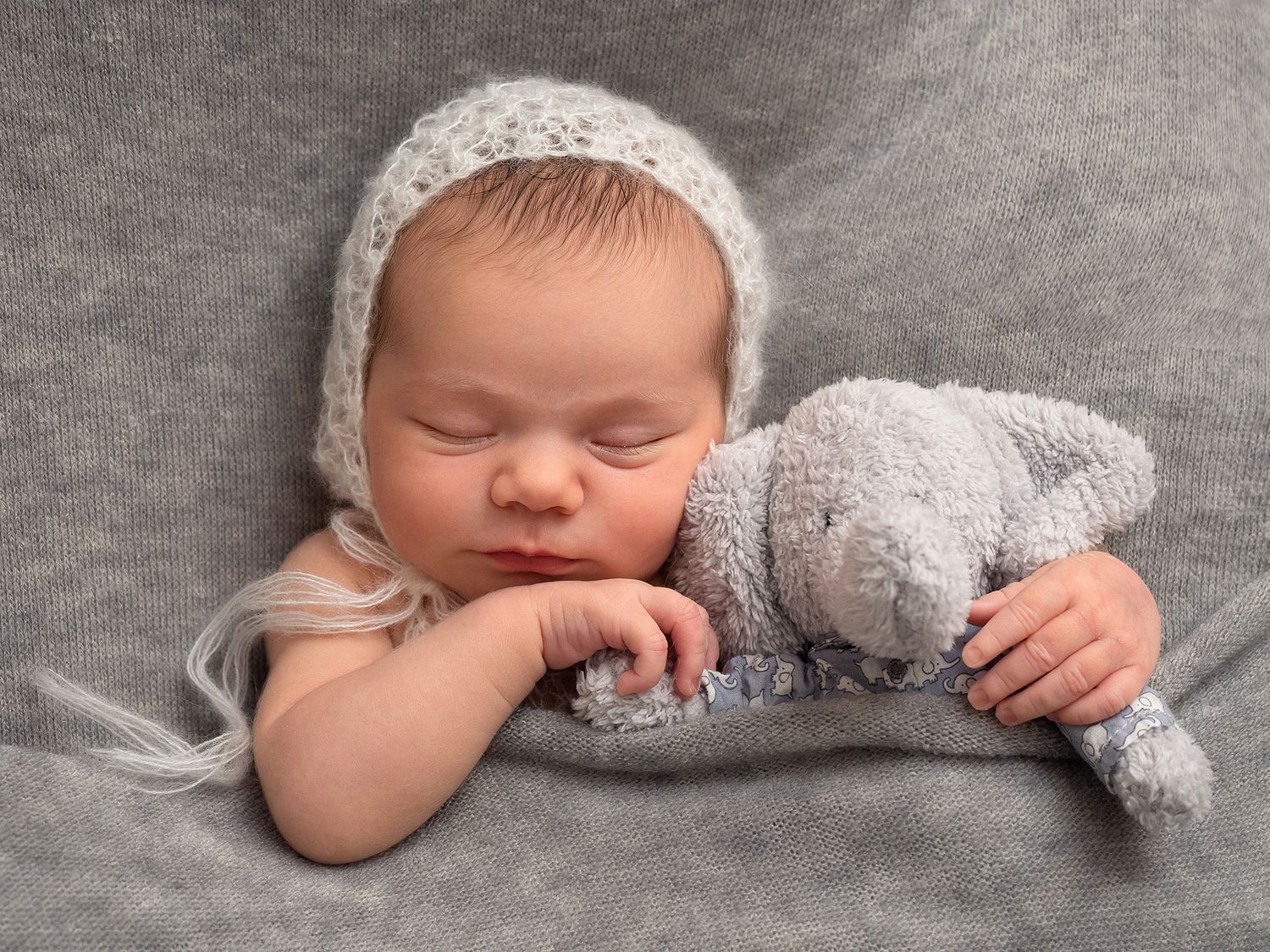 baby tucked in bed with a toy elephant