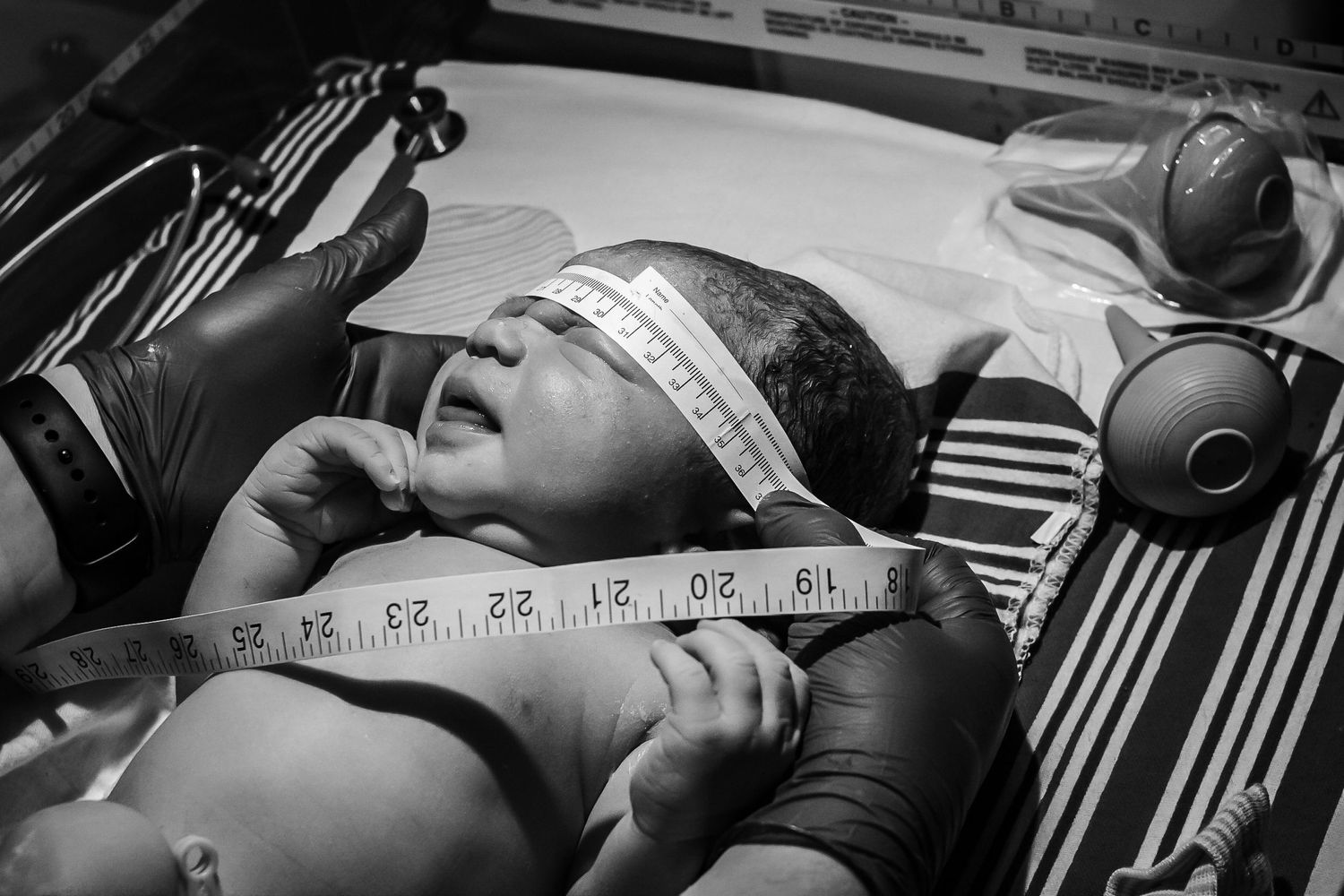 Newborn baby on the warmer as the nurse takes his measurements just after birth in Sioux City, IA.