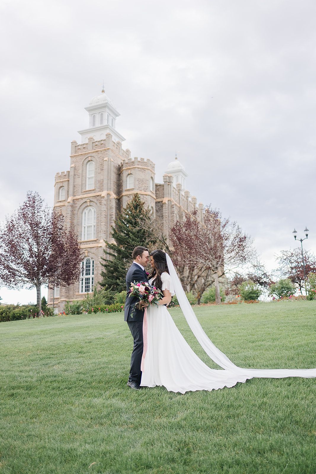 Wedding portrait in front of a beautiful stone temple with a long flowing veil.