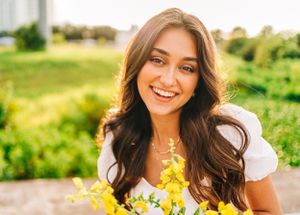 Portrait of woman holding yellow flowers outdoors in spring.