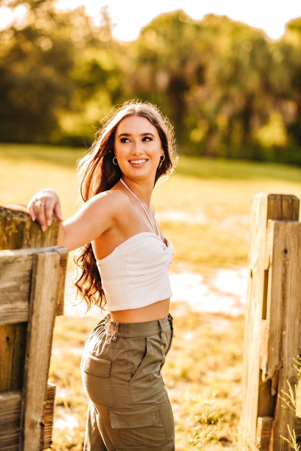 Athletic summer style with crop top and cargo pants against golden sunset lighting.