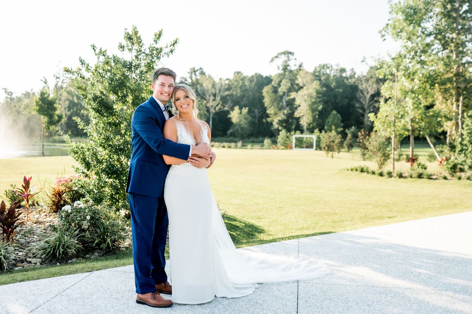 Wedding couple and party members pose together outdoors at venue.
