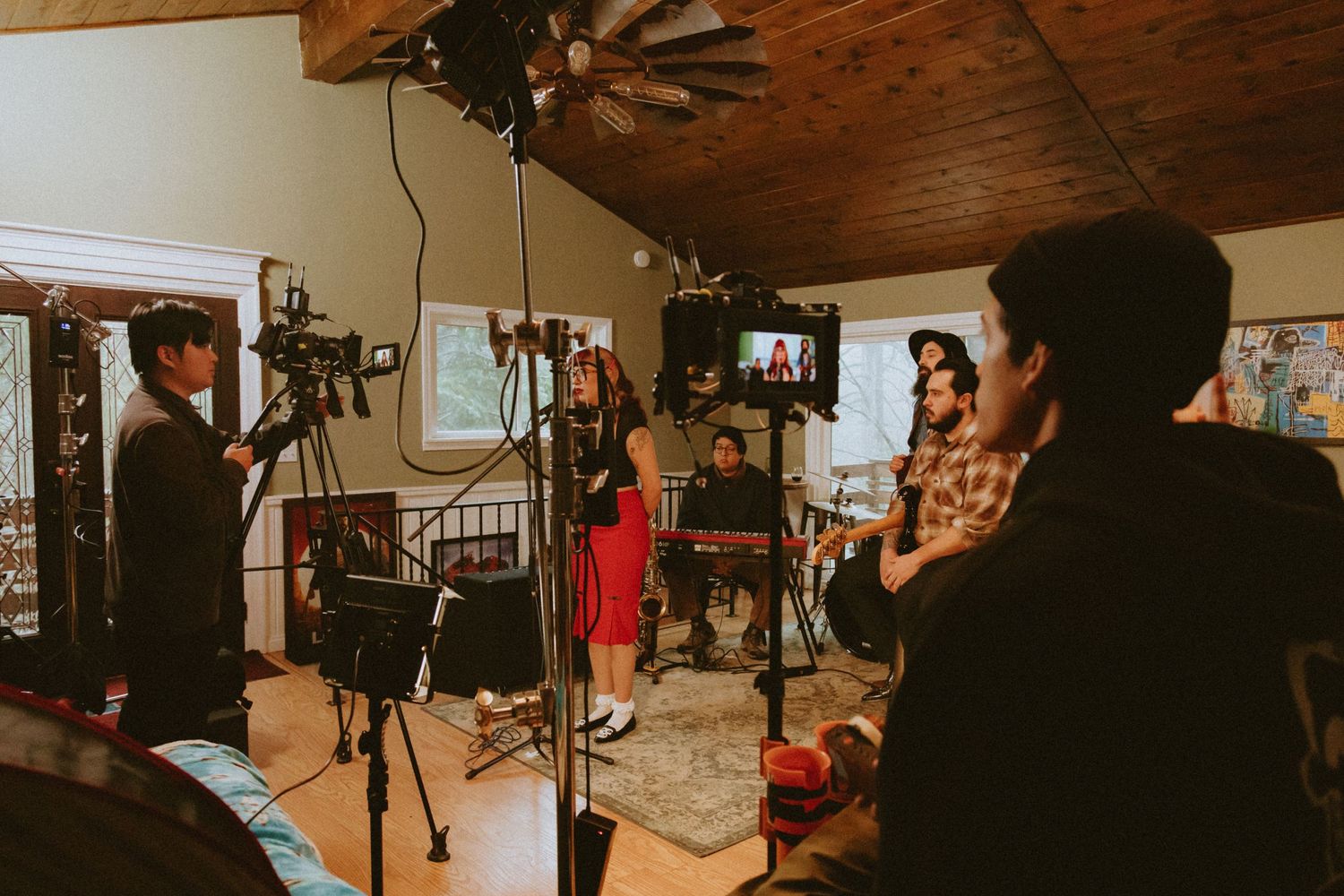 Behind the scenes of a video production with cameras and crew in a rustic indoor setting.