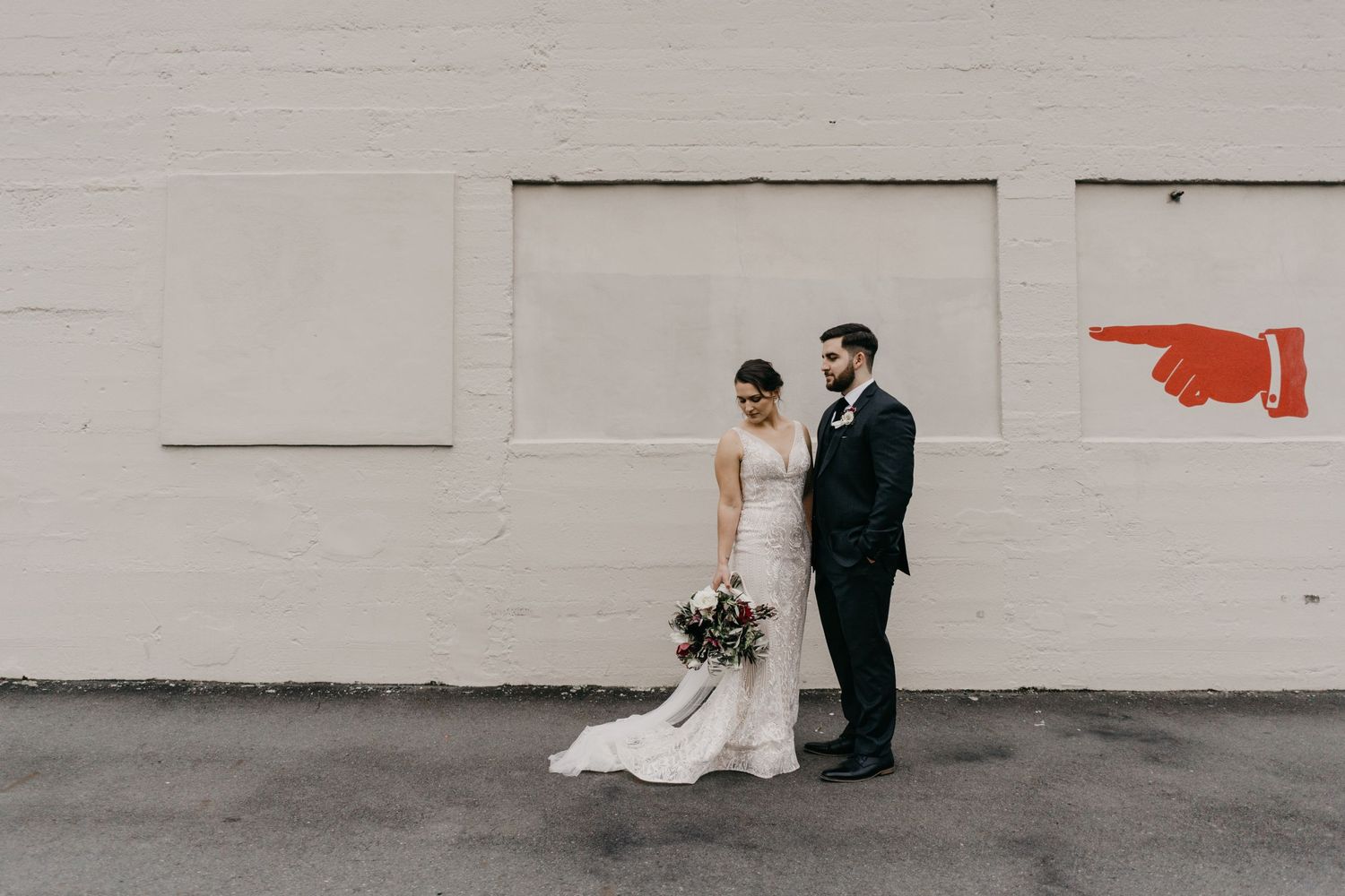 Charming Hamilton, New Zealand couple sharing a tender moment during their urban wedding photo shoot. The cityscape prov