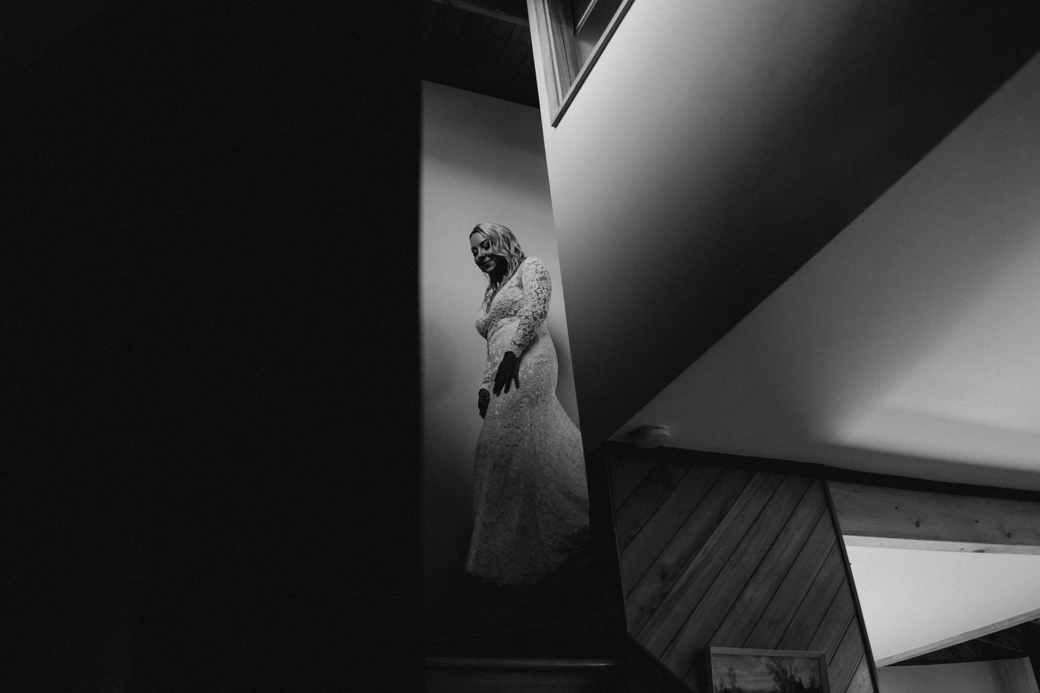 Graceful bride in Raglan, New Zealand, descending a staircase adorned with elegance, wearing a stunning wedding gown. Th