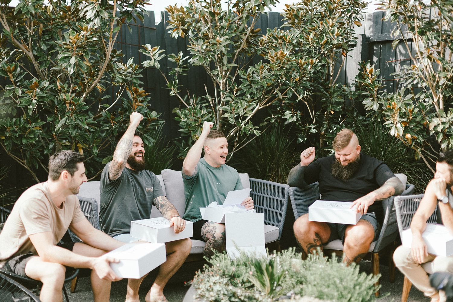 Friends gathered on outdoor couch sharing excitement while reading papers together.