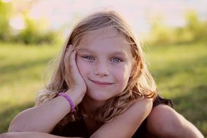 Golden hour portrait of a young child resting their head on their hand outdoors.