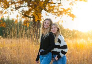 Outdoor autumn portrait at sunset with golden light filtering through trees.