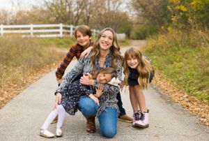 Family group with small dog posing on rural path during fall season.