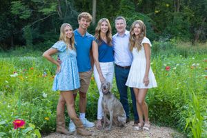 Family portrait with their dog in a wildflower meadow on a summer day.