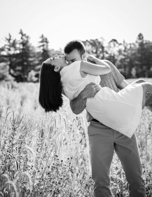 Romantic couple embracing and sharing an intimate moment in a sunlit field.