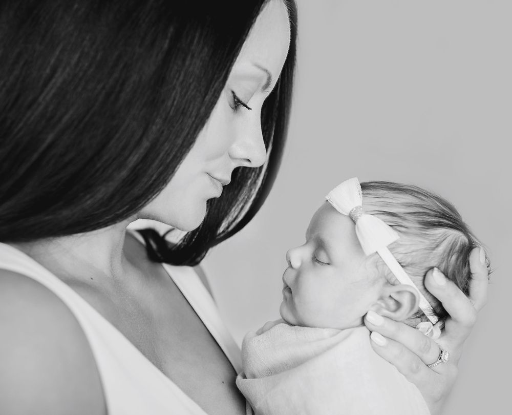 A black and white artistic portrait capturing a tender moment between mother and infant.