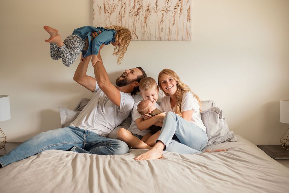 A joyful family moment playing together on a bed with natural lighting.