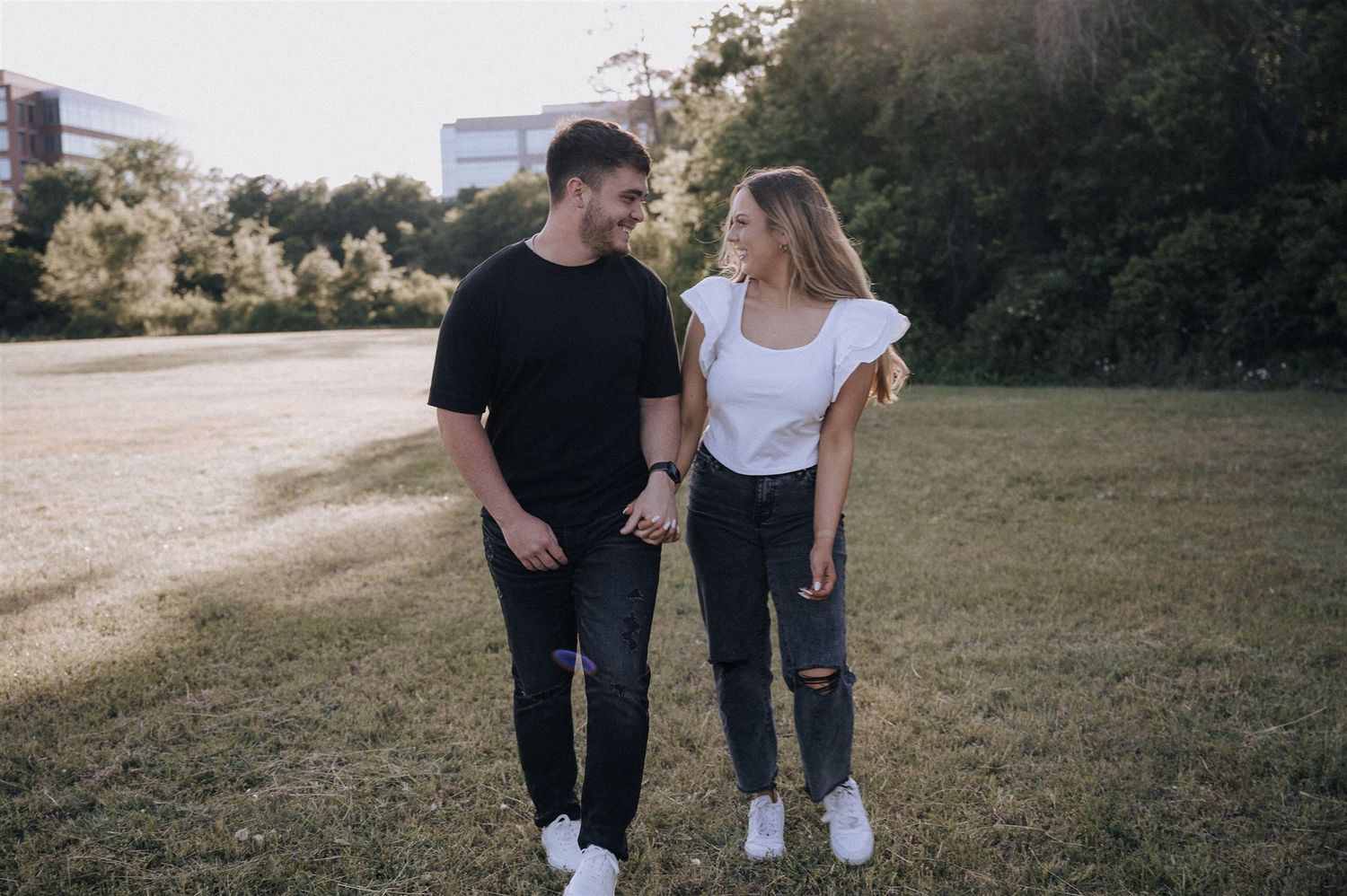 Casual couple in matching black and white outfits walking together in a grassy field.