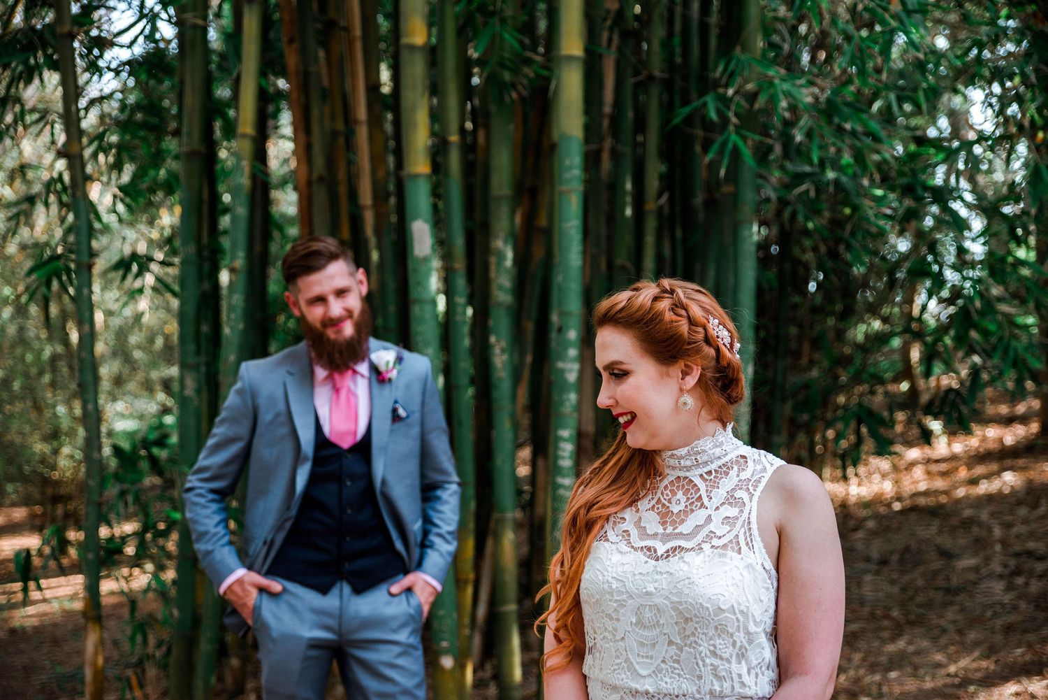 Intimate wedding photo in a bamboo forest with a lace dress and blue suit.